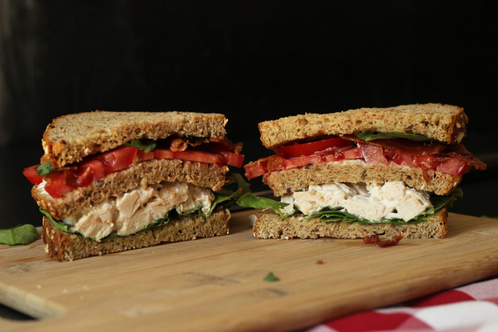 sandwich cut in half on cutting board.