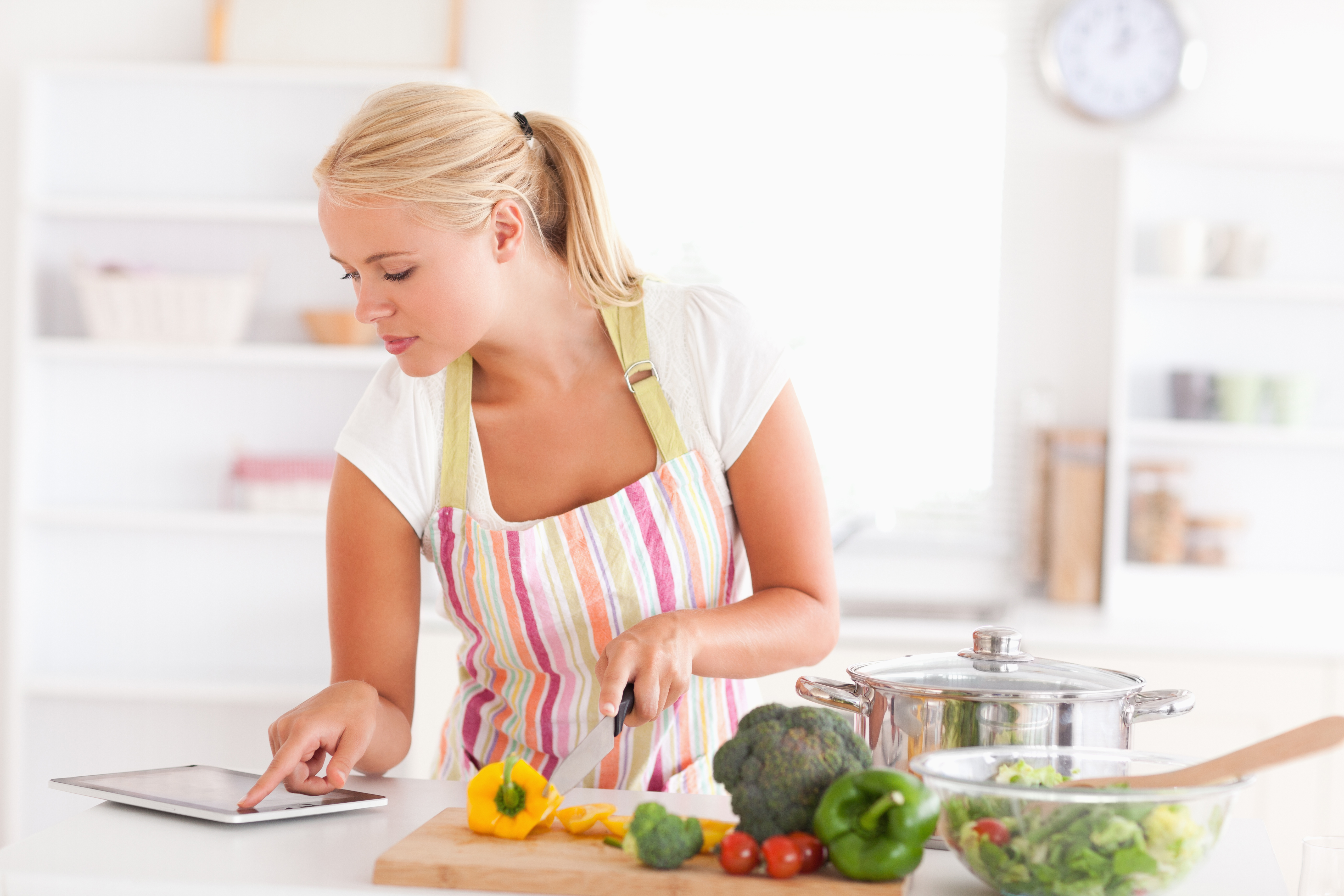 Blonde woman using a tablet computer to cook